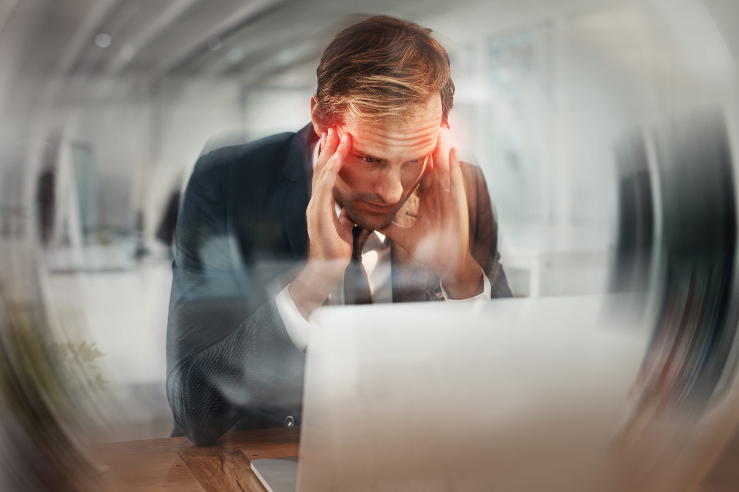 Laptop, blur and business man with headache, stress and deadline at night in office. Pain, sick and tired employee with migraine on computer, vertigo and massage temples for brain fog with red glow.